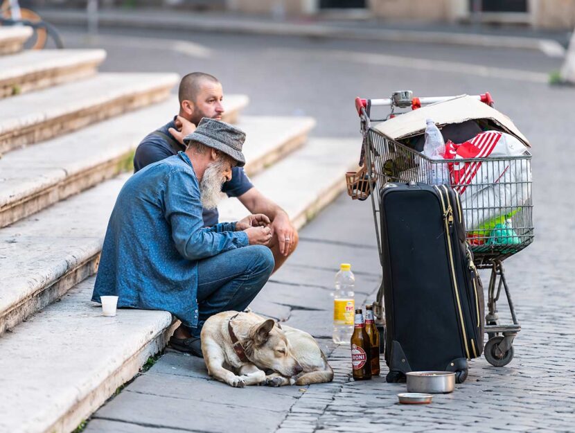 Senza tetto seduti su scalinata a Roma