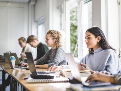 una fondatrice di startup che è una bellissima donna islamica alla scrivania  con un laptop alza le mani per congratularsi con il successo delle piccole  attività di e-commerce di uffici. giovane manager