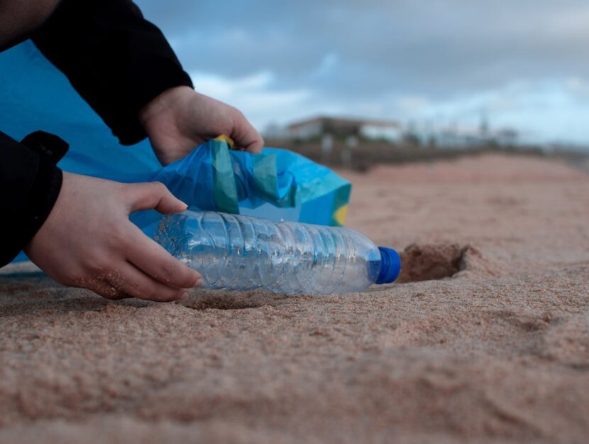 un volontario sta raccogliendo una bottiglia di plastica dalla spiaggia