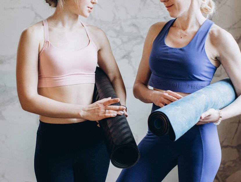 due ragazze in tenuta fitness con il loro tappetino yoga sotto il braccio