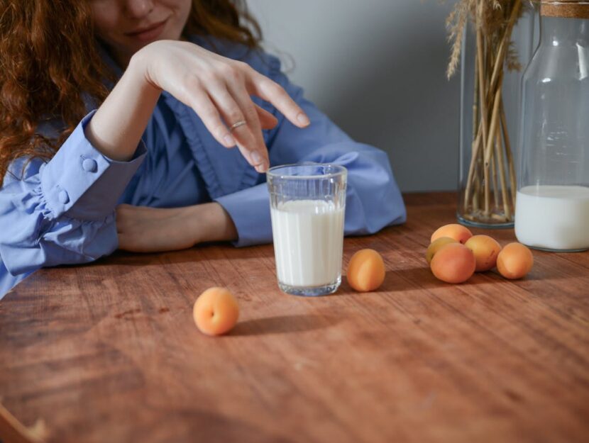 albicocche appoggiate su un tavolo accanto a un bicchiere di latte