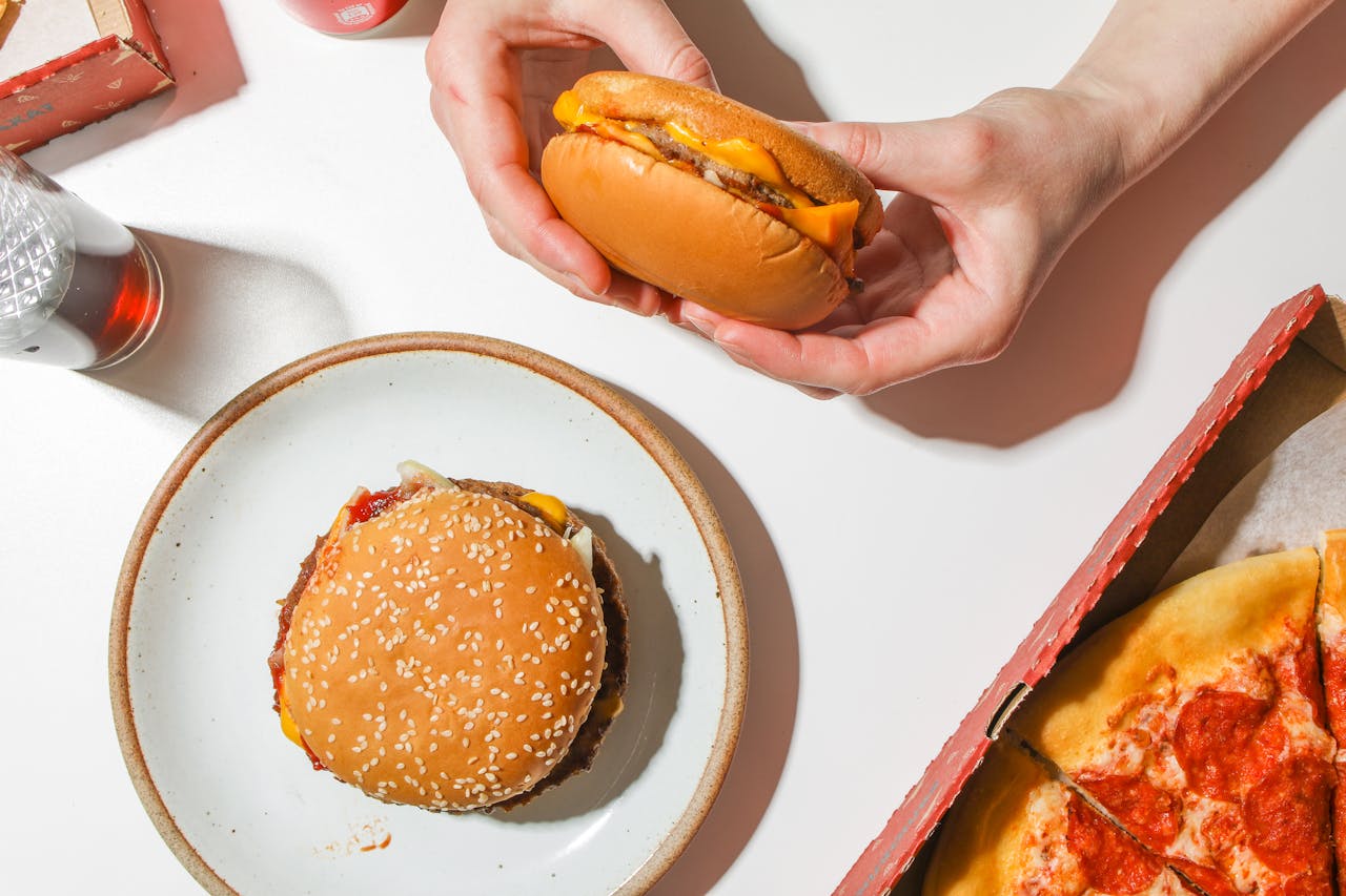 mani che mangiano hamburger e junk food