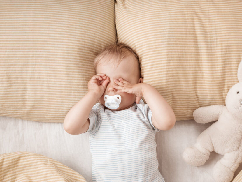 bambino con ciuccio si sta svegliando nella sua culla