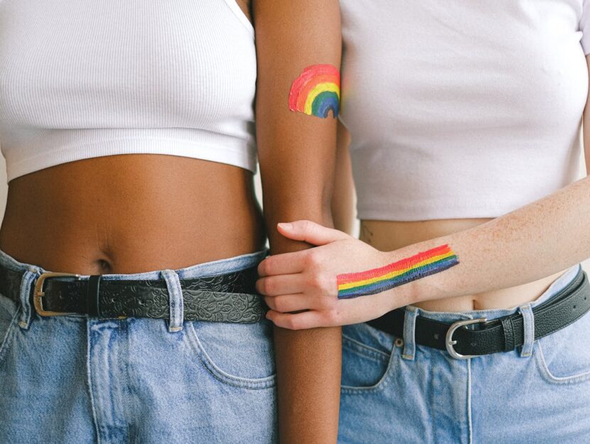 ragazze si abbracciano con la bandiera lgbtq+ dipinta sul braccio