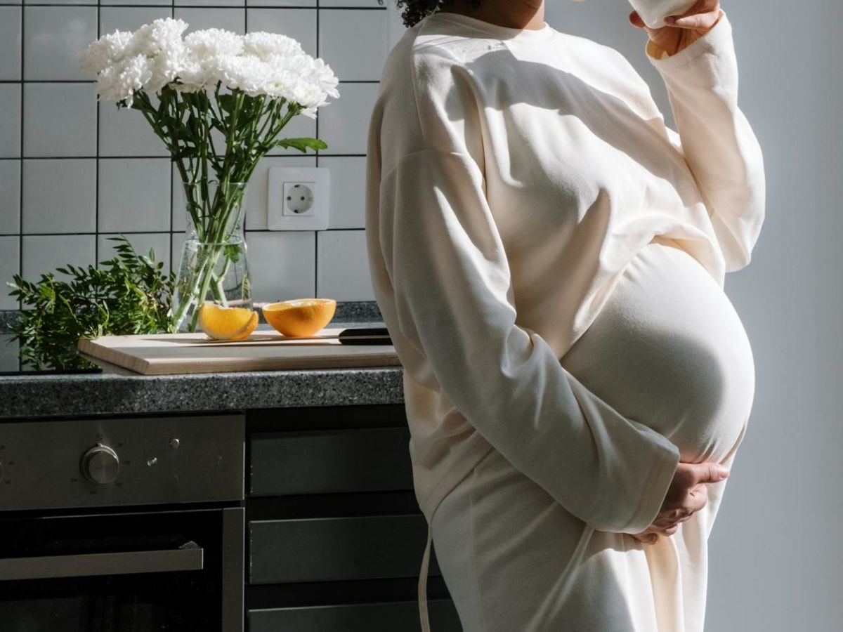 donna incinta in cucina che beve