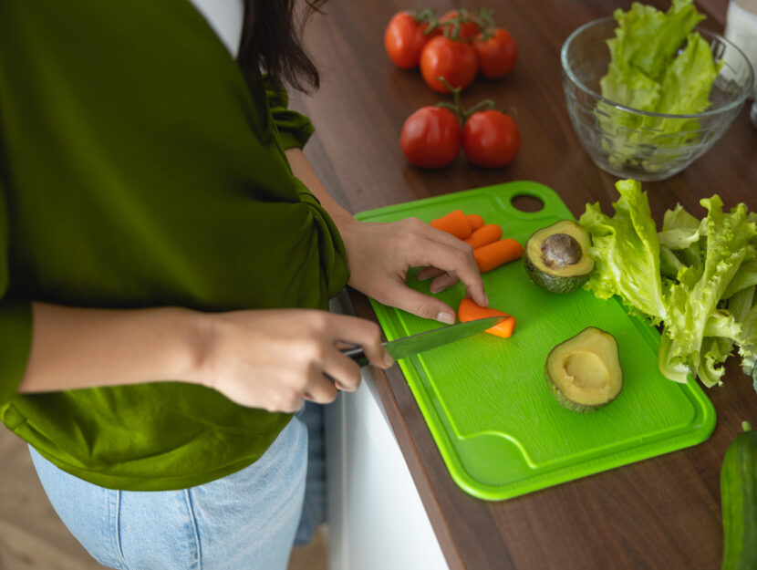 ragazza sta tagliando la verdura su un tagliere di plastica