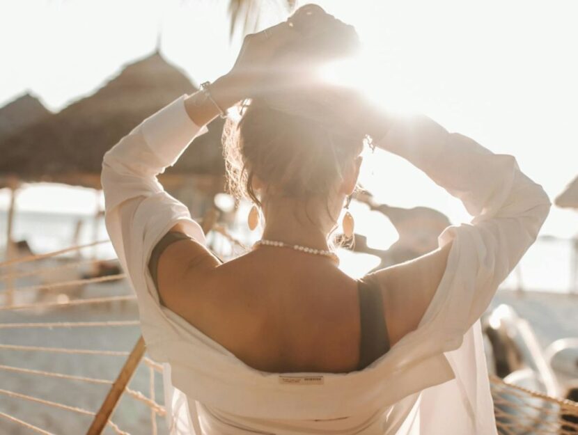 ragazza in spiaggia si raccoglie i capelli in uno chignon