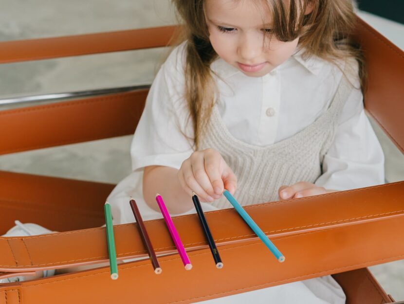 bambina che allinea i colori a pastello sulla sedia