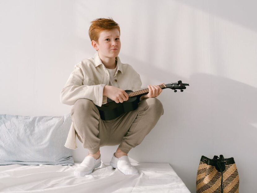 ragazzo sta suonando l'ukulele sul letto