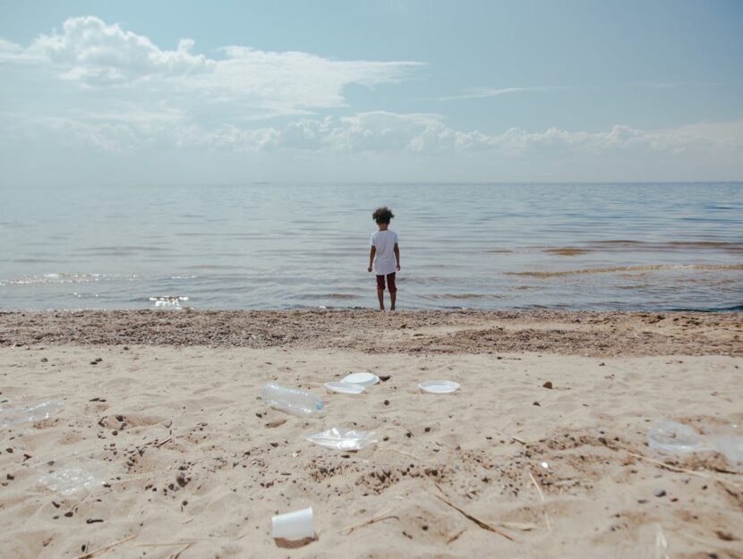 bambino in spiaggia con bottiglie sulla sabbia