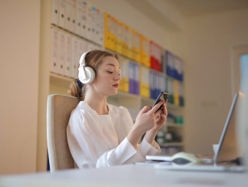 persona a lavoro con cuffie che guarda il telefono