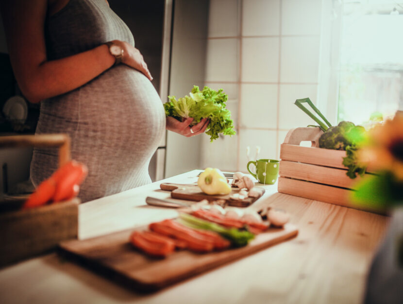 ragazza incinta sta cucinando delle verdure