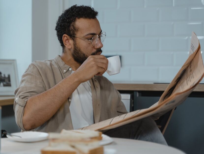 ragazzo la mattina che beve caffè e legge il giornale