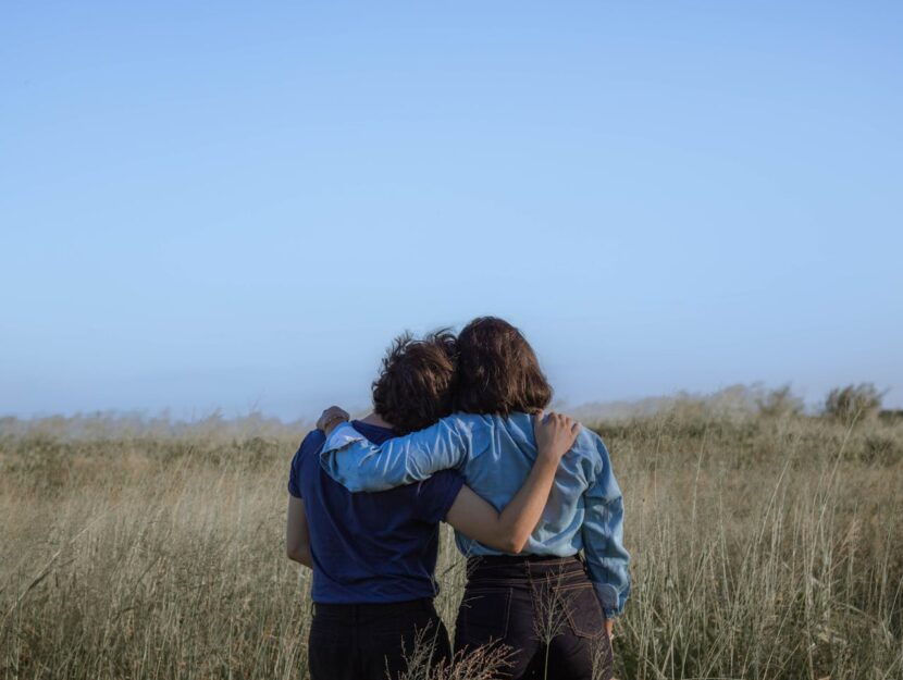 ragazze di spalle che si abbracciano in un campo