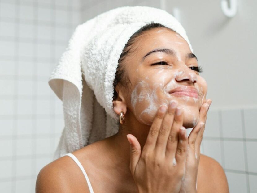 ragazza si sta lavando il viso in bagno allo specchio