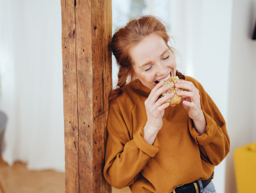 ragazza appoggiata allo stipite che mangia il pane