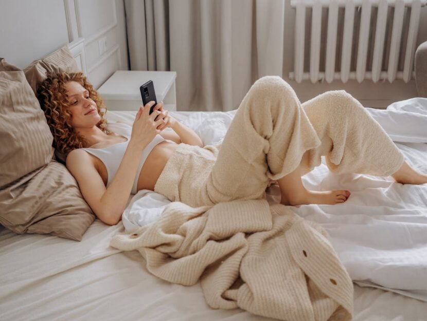 ragazza che guarda il telefono nel letto in pigiama