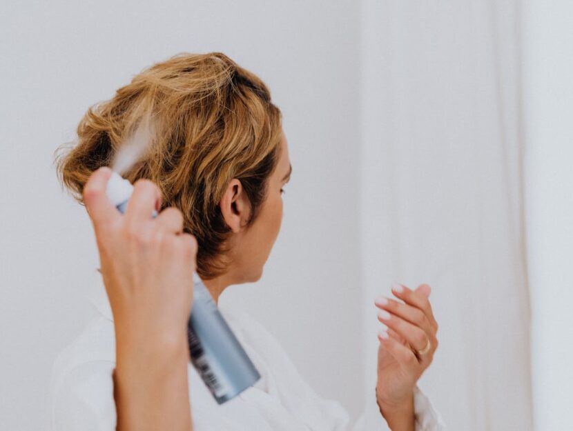 Ragazza che si sta mettendo uno spray sui capelli