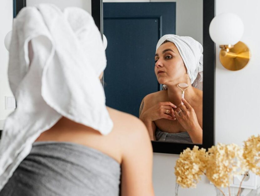 ragazza con rullo di giada mentre fa la beauty routine allo specchio