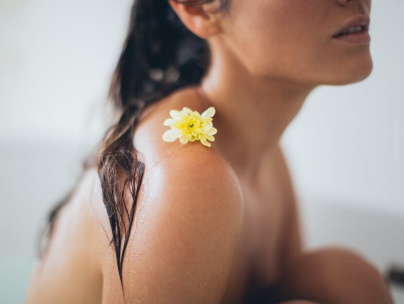 ragazza nella vasca da bagno con fiore sulla spalla