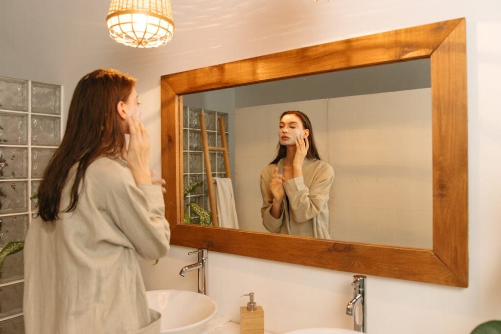 ragazza si fa una maschera al viso allo specchio