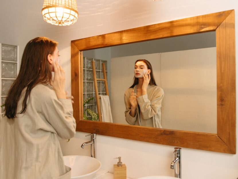 ragazza si fa una maschera al viso allo specchio