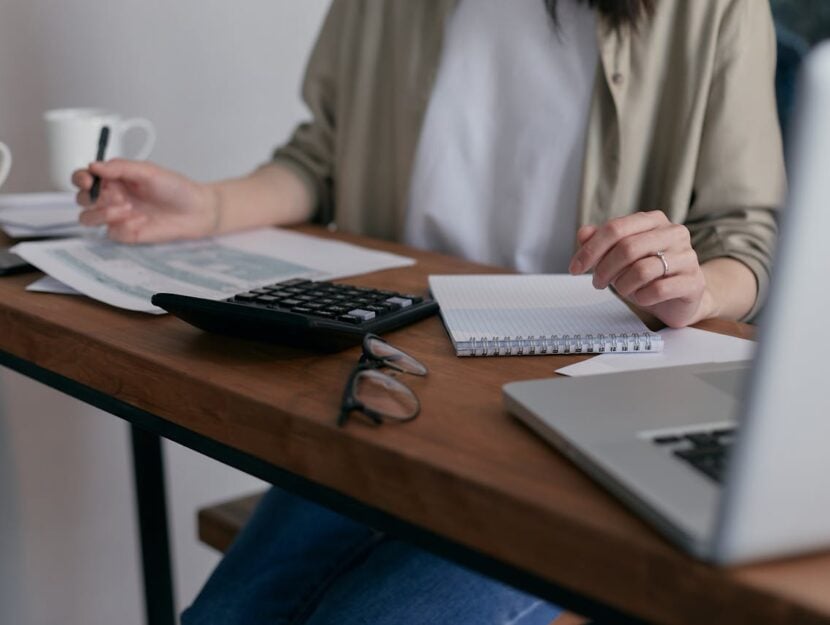 persona al computer che sta facendo i conti con una calcolatrice