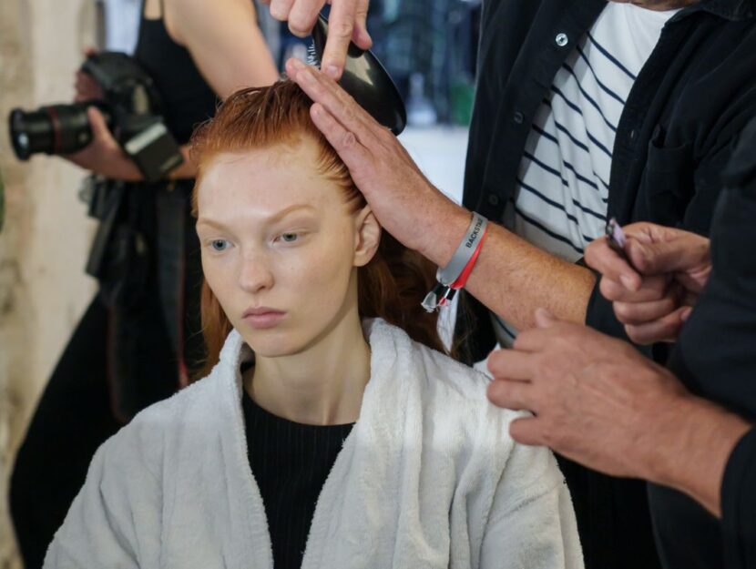 modella si sta facendo pettinare i capelli prima di una sfilata