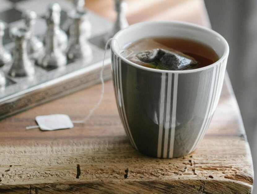 tazza di the poggiata sul tavolo con scacchiera dietro