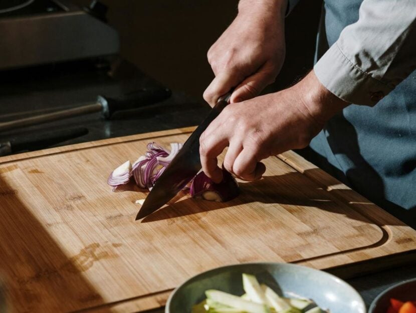 uno chef sta affettando la cipolla su un tagliere