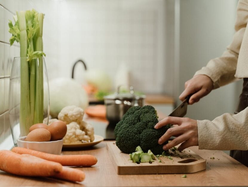 ragazza che taglia un broccolo sul tagliere