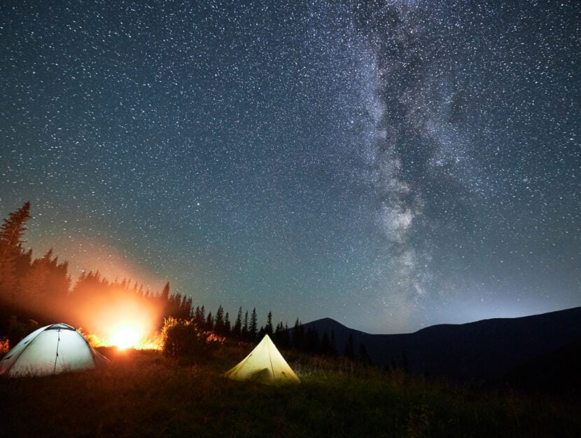 cielo stellato in montagna e persone in tenda