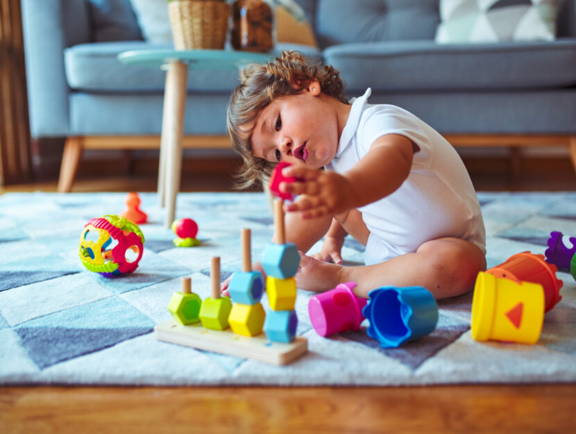 bambino che gioca con giocattoli sul tappeto